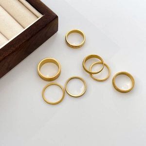 Close-up of seven assorted 18K gold-plated titanium steel rings with matte and star textures