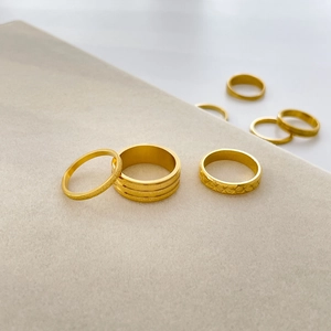 Detail of matte gold rings with star engravings and textured layers on velvet