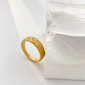 Close-up of star engraved 18K gold plated titanium steel ring on textured stone