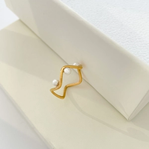 Macro view of wave shaped 18K gold ring featuring three small freshwater pearls