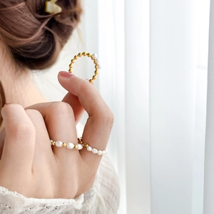 Detail of three freshwater pearl and gold-plated steel rings worn on a hand