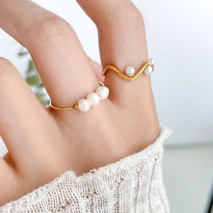 Detailed macro view of 18K gold plated freshwater pearl rings with beaded wave design