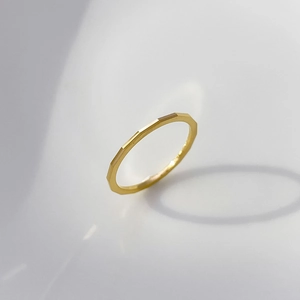 Detailed macro view of a minimalist gold ring with geometric faceted cutting texture