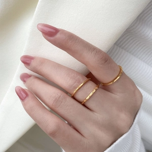Detail of three-piece hammered gold ring set with geometric facets for stacked styling