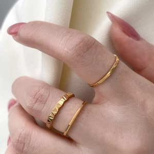 Detailed view of three stacked gold geometric faceted and minimalist rings on finger