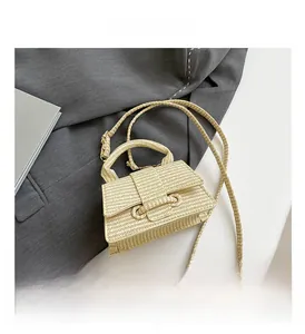 Detail of beige woven straw handbag featuring a rectangular flap and woven handle