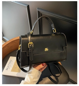 Detail of black leather handbag with gold logo, top handle and adjustable shoulder strap
