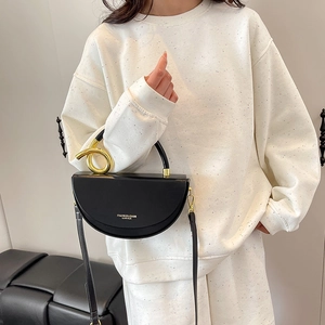 Chic black saddle bag with a unique gold spiral handle and leather crossbody strap