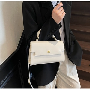 Close-up of ivory crossbody bag with gold buckle on wooden stairs background