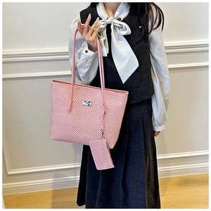 Pink herringbone tote bag with small matching pouch shown on a gray vest and white shirt