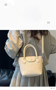 Detail view of beige lychee grain leather bucket bag with metallic feet and snap closure
