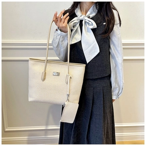 Detail of herringbone woven tote bag with matching pouch and metal logo on strap