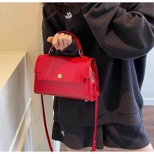Detailed view of red leather crossbody bag with envelope flap and gold metal logo