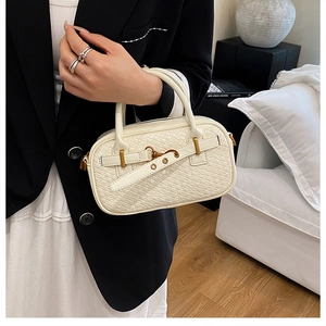 Détail du sac polochon blanc crème avec texture cuir gaufré et boucles métalliques dorées