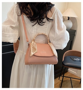Pink crossbody bag detail featuring woven texture, silk scarf handle, and fashion text