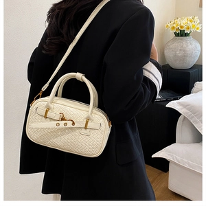 Détail d'un sac à main blanc à texture tissée avec boucle dorée et bandoulière longue