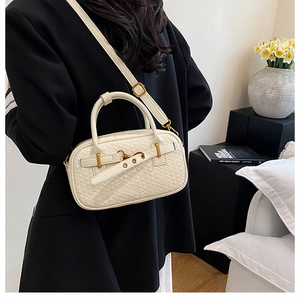 Détail d'un sac bandoulière beige tissé porté par un mannequin en décor minimaliste