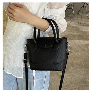 Detail of black lychee texture bucket bag with silver feet and adjustable strap on model