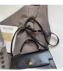 Detail of black leather handbag with gold metal clasp and adjustable shoulder strap