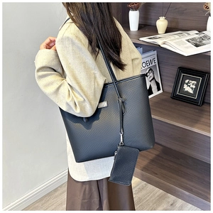 Detail of black perforated tote bag with matching small pouch and silver logo hardware