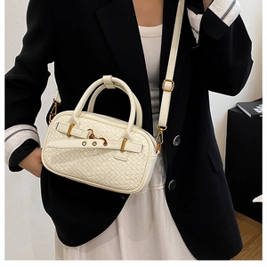 Détail du sac Boston blanc à texture tressée avec boucles métalliques dorées