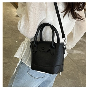 Detail of black lychee grain leather bucket bag with top handle and fine shoulder strap