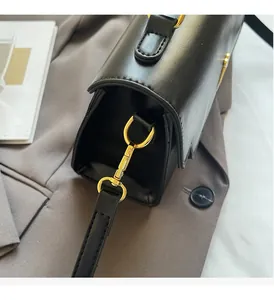 Detailed close-up of golden metal buckles and black grain leather on a crossbody bag
