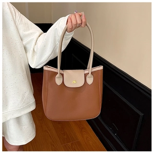 Detail of two-tone tote bag featuring pebble grain texture and elegant gold logo