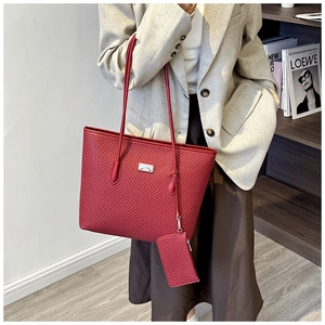 Detail of red herringbone woven tote bag with matching pouch and metallic logo plaque