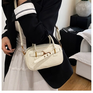 Détail d'un sac à main blanc à motif crocodile avec fermoir doré et bandoulière réglable