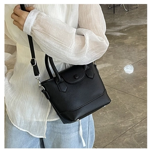 Detailed side view of black lychee grain leather mini bucket bag worn as a crossbody