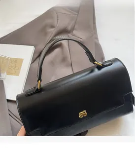 Classic black leather handbag with gold logo detail on a grey suit jacket background