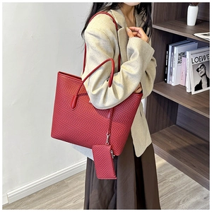 Detail view of burgundy herringbone tote bag with matching leather straps and mini pouch