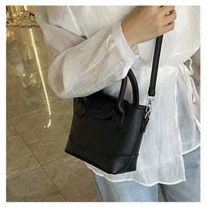 Detail of black lychee grain faux leather bucket bag with silver hardware and strap