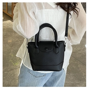 Detail of a black lychee texture bucket bag showing the snap button closure and strap