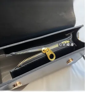 Detail of smooth golden metal zipper and magnetic buckle on black leather phone bag