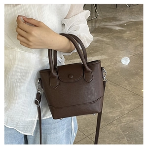 Detail of dark brown lychee leather texture and silver hardware on a bucket bag