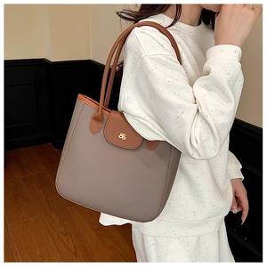 Close-up of taupe tote bag with lychee texture and golden S-shaped metal hardware