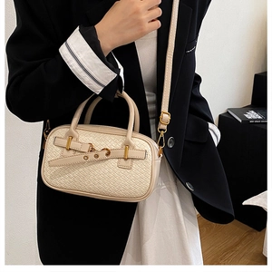 Détail de la texture en cuir tressé crème avec boucle dorée et bandoulière