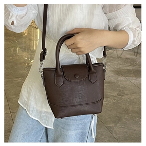 Detail of dark brown lychee texture bucket bag with round handles and adjustable strap