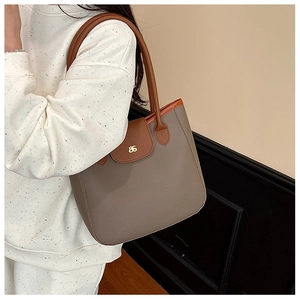 Detailed texture of lychee grain leather on a taupe and brown contrast tote bag