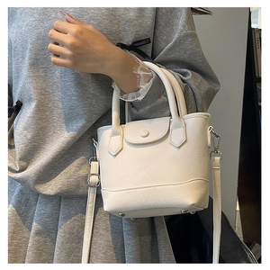 White mini bucket bag in lychee pattern leather styled as a crossbody on a model