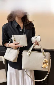 Detail of four-piece beige embossed handbag set with a teddy bear charm for women