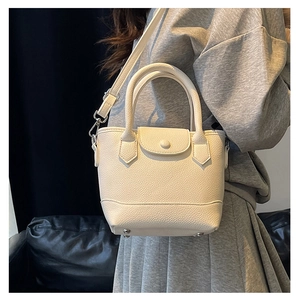 Detail view of white lychee leather bucket bag with metal studs and top handle strap