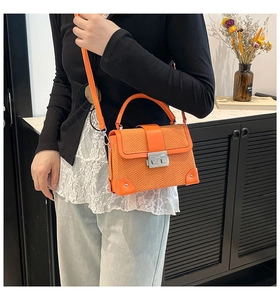 Model wearing a bright orange box bag with snake pattern flap and silver twist lock