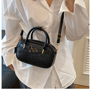 Détail du sac à main noir tressé avec garnitures dorées porté par un mannequin