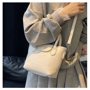 Close-up of white lychee-patterned tote bag with metallic feet and magnetic closure