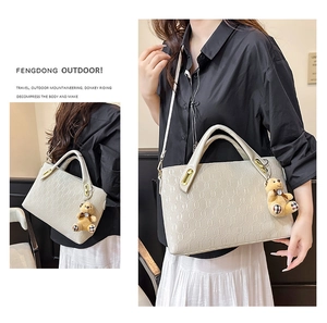Close-up of beige tote bag with chain embossed texture and cute bear pendant charm