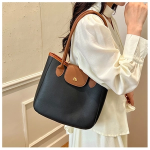 Side view of bicolor tote bag featuring black pebbled texture and brown leather straps
