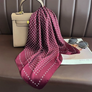 Polka dot silk scarf in burgundy red hanging on a luxury handbag for a chic style